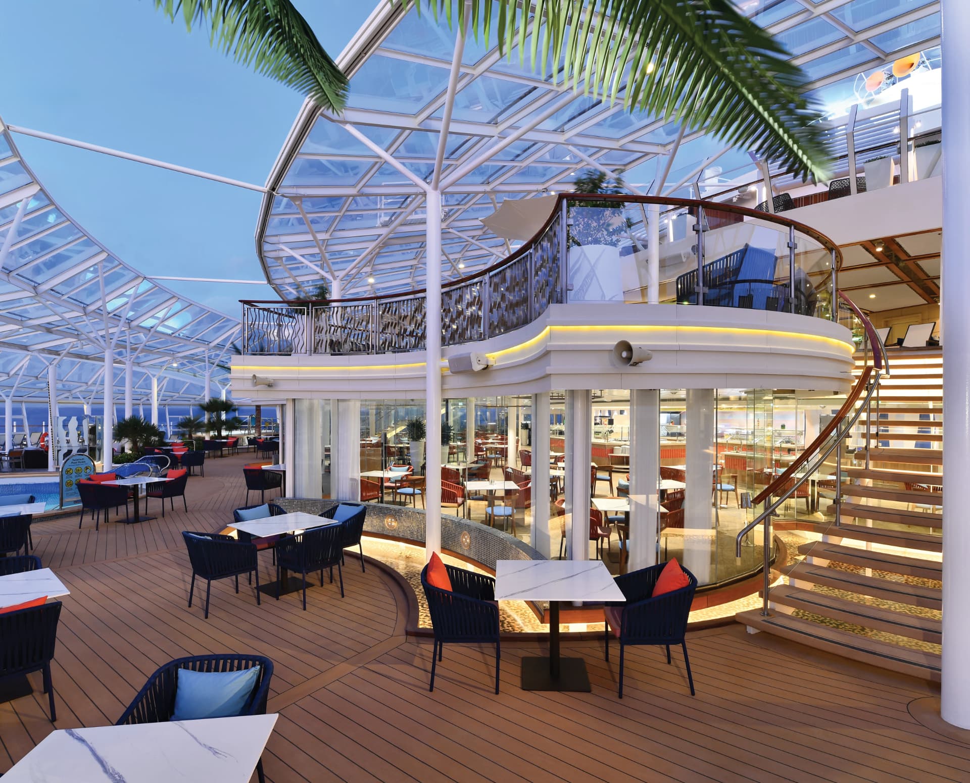 Solarium Bistro dining terrace under a glass canopy at dusk aboard Oasis of the Seas