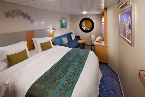 Interior Cabin with king bed, sofa, desk, and modern cruise decor aboard Oasis of the Seas